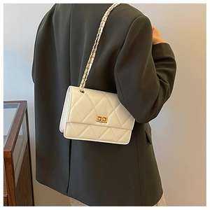 Sac à bandoulière matelassé beige porté, avec chaîne dorée et boucle carrée en métal