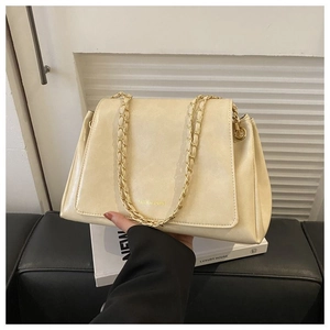 Detail of beige faux leather tote bag with gold chain straps and textured surface finish