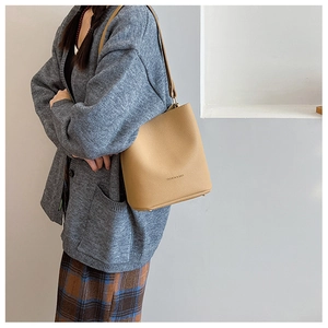 Detail of khaki bucket bag with pebbled leather texture and gold fashion logo