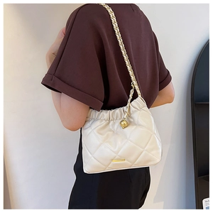 Detail view of cream leather quilted shoulder bag with gold chain and drawstring closure