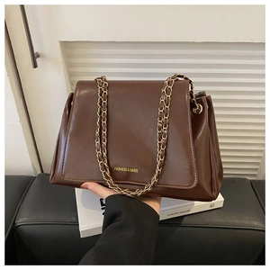 Detail of dark coffee PU leather shoulder bag with golden chain and embossed fashion text