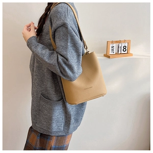 Detail of light brown lychee grain leather bucket bag with adjustable shoulder strap and studs