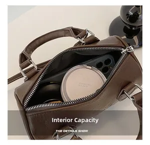 Internal capacity of the dark brown Boston bag showing phone and cosmetics