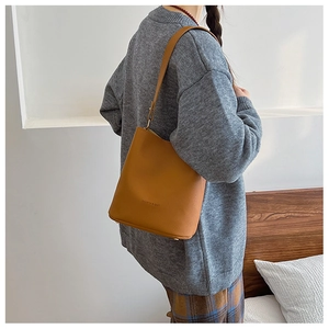 Detail of vintage brown textured leather bucket bag with metal protective feet on base