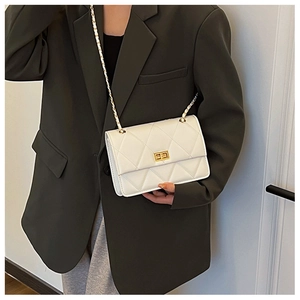 Détail du sac en cuir blanc matelassé avec chaîne dorée porté sur une veste verte