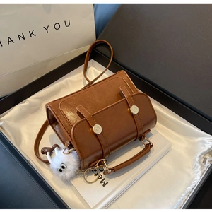 Detail of brown vintage crossbody bag in gift box with plush charm and gold buckle