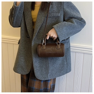Close-up of the brown leather Boston bag featuring embossed logo and metal ring hardware