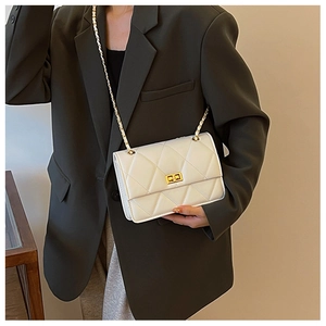 Vue détaillée du sac matelassé blanc avec chaîne dorée sur une veste blazer olive