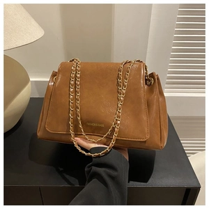 Detail of a brown crossbody tote bag with a golden chain strap and logo lettering
