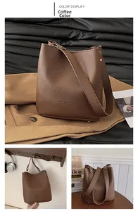 Detail of coffee brown pebbled leather bucket bag with logo and anti-wear bottom studs