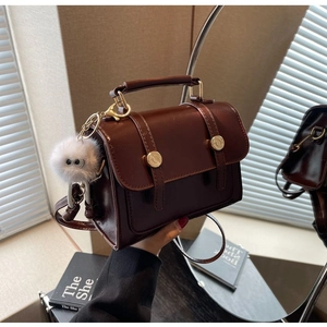 Detail of dark brown vintage handbag with gold buckles and fluffy monster charm