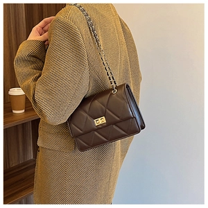 Détail du sac bandoulière marron foncé matelassé avec chaîne dorée et fermoir pivotant