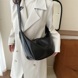 Sac hobo vintage en similicuir noir porté avec un trench-coat élégant pour femme