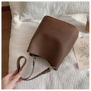 Macro detail of brown lychee grain leather bucket bag with gold hardware and embossed logo