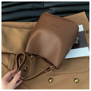 Detail of brown litchi pattern bucket bag with FASHION & BAGS text and adjustable strap