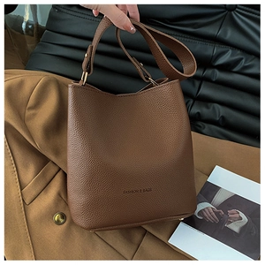 Close-up of brown litchi pattern bucket bag showing metal studs and fashion text