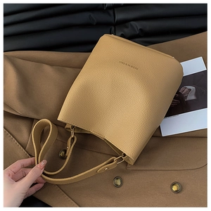 Detailed macro view of khaki lychee leather texture and FASHION & BAGS logo on bucket bag
