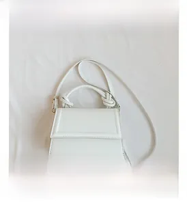 Détail du mini sac blanc à bandoulière avec poignée nouée et boucles latérales en métal