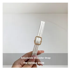 Détail d'une bandoulière réglable en similicuir blanc avec une boucle en métal doré
