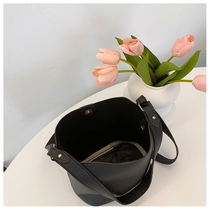 Top view of black bucket bag interior showing pebbled leather texture and zipper pocket