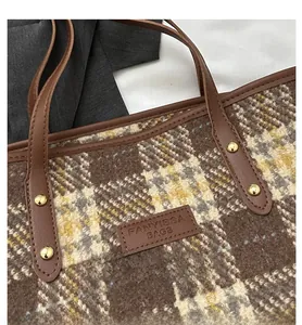 Nahaufnahme der karierten Tweed-Tasche mit Lederetikett und Metallnieten-Details