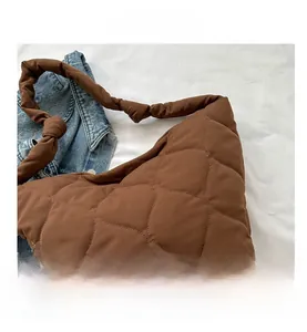Detail of coffee brown quilted shoulder bag featuring unique knotted strap design