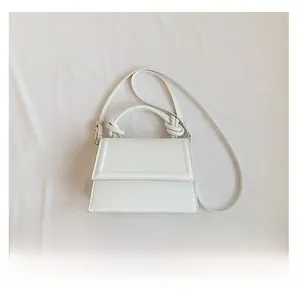 Détail du sac à main blanc avec poignée nouée et smartphone pour comparer la taille