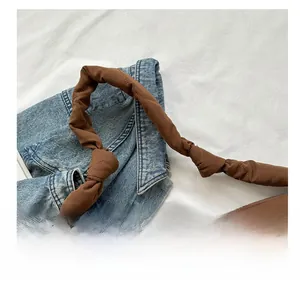 Close-up of quilted tote bag with twisted handle and brown glossy finish on denim background