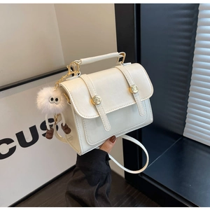 Detailed shot of white faux leather crossbody bag with gold buckle and fuzzy charm