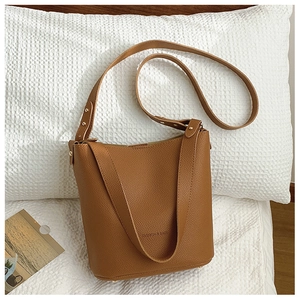 Close-up of caramel leather bucket bag with textured finish and golden metal feet
