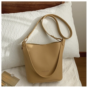 Detailed close-up of ginger yellow leather bucket bag with pebble grain texture and adjustable strap