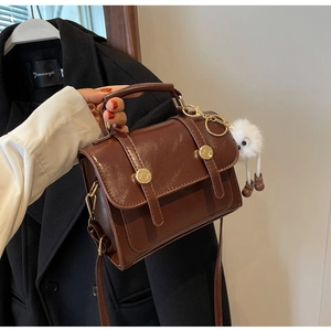 Brown retro leather small square bag with dual gold buckles and plush monster charm