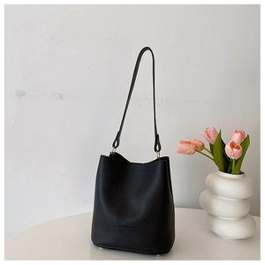 Detailed view of black litchi grain leather bucket bag with gold ring hardware