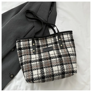 Detailaufnahme der karierten Tweed-Tragetasche mit dicker Wolltextur und Ledergriff-Details