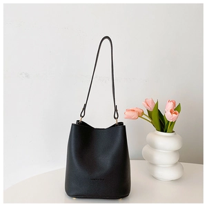 Detail of black lychee grain leather bucket bag with gold hardware and pink tulips