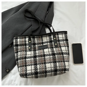 Nahaufnahme der Tweed-Tasche mit Hahnentrittmuster, schwarzem Ledergriff und Goldnieten