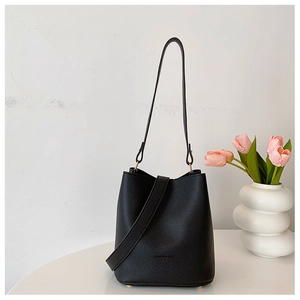 Detail of black lychee grain leather bucket bag with fashion logo on white background