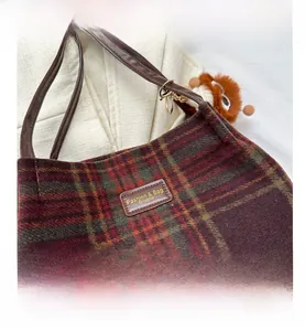 Close-up of retro plaid shoulder bag featuring leather tag and cute brown plush charm