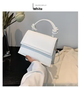 Gros plan d'un sac à main blanc en cuir avec une poignée ronde à nœud distinctive