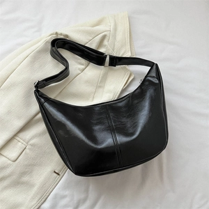 Detailed view of black patent PU leather half-moon bag with silver buckle and stitching