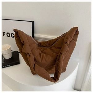 Detail of dark brown heart-quilted puffer tote bag with spacious zipper closure