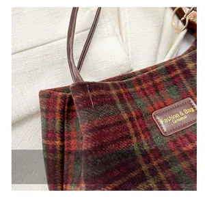 Close-up of classic red and green plaid fabric with leather patch on tote bag