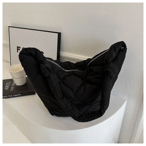 Detail of black quilted puffer bag showing soft padded texture and half-moon silhouette