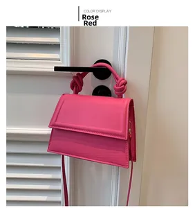 Détail du sac bandoulière rose fuchsia avec poignée nouée suspendu à la porte