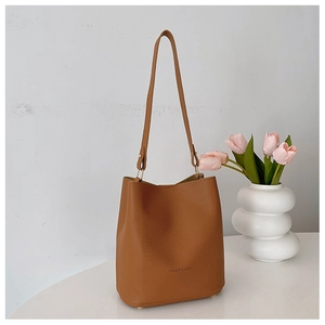 Detail of brown bucket bag showing lychee grain texture and gold metal accents