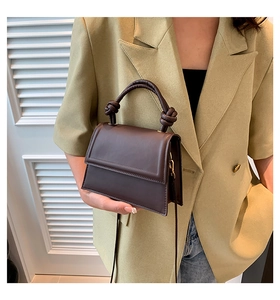 Détail d'un mini sac à main marron foncé en cuir avec poignée nouée et bandoulière chic