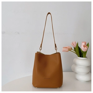 Brown lychee texture bucket bag with Fashion & Bags lettering on a white table