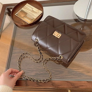 Sac bandoulière matelassé chic marron foncé posé sur une table décorative en bois