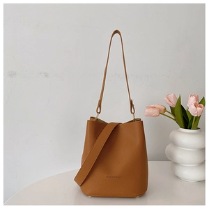 Detail of brown litchi pattern bucket bag with FASHION & BAGS text on white table