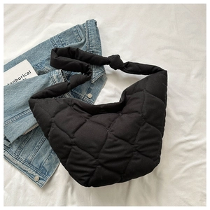 Close-up of black quilted puffer bag with large diamond stitching and knotted shoulder strap